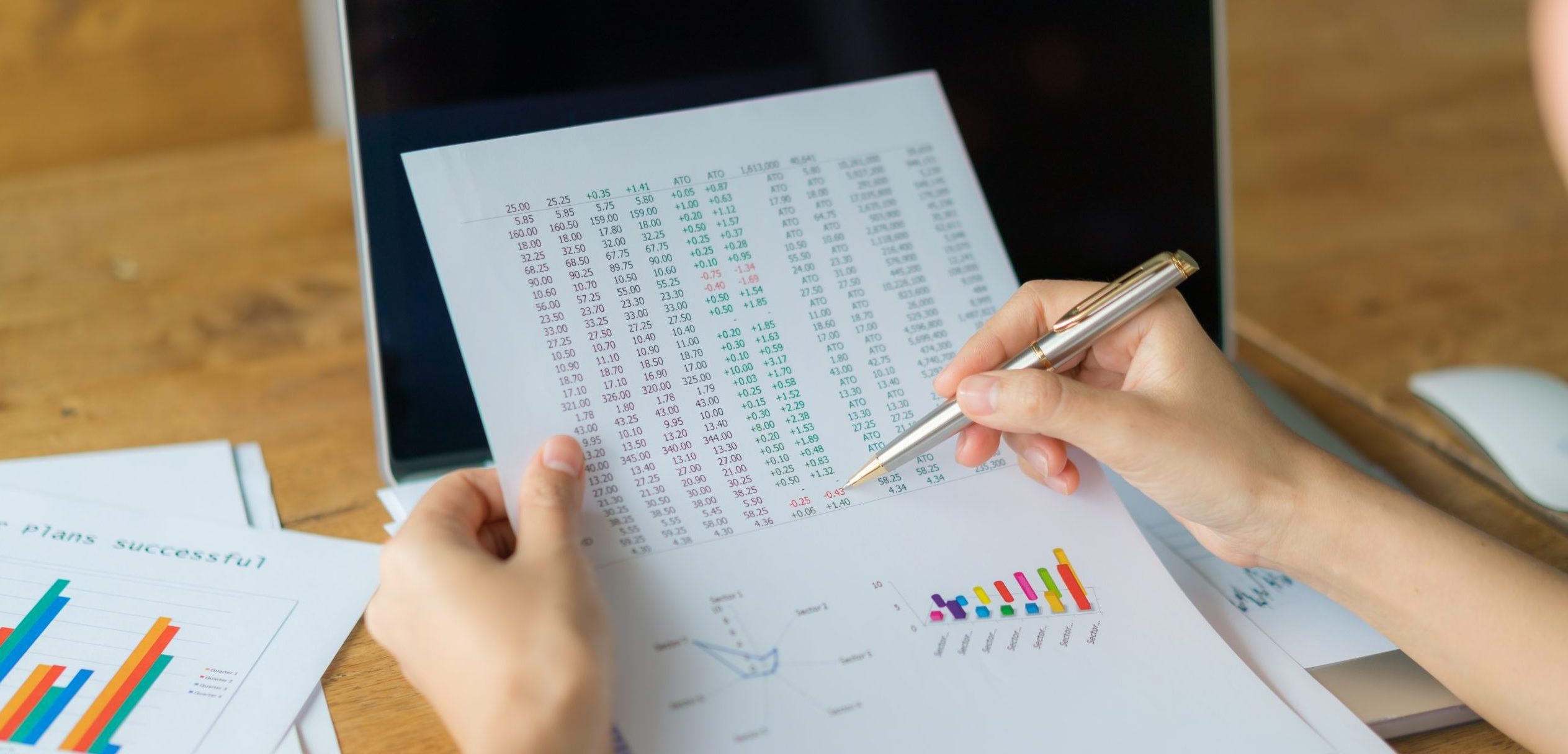 Business woman hand with Financial charts and laptop on the tabl